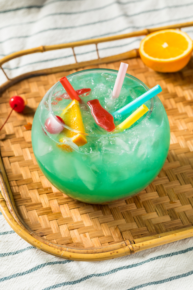 A blue fishbowl cocktail filled with colorful straws and Swedish fish