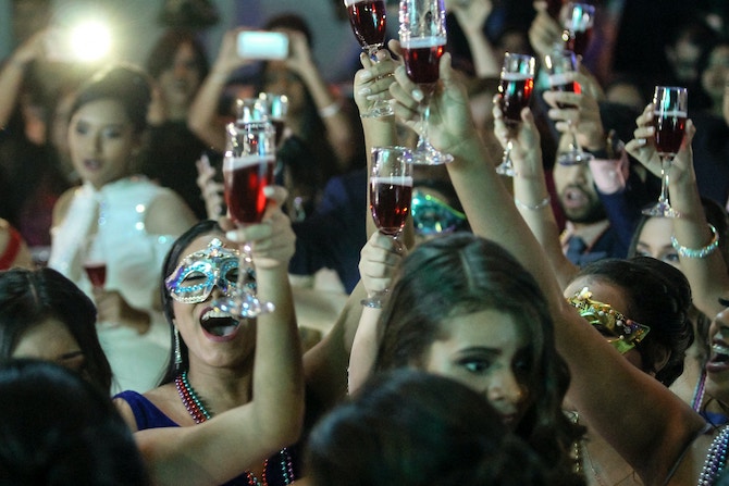 A group of people holding up their drinks at a masquerade party