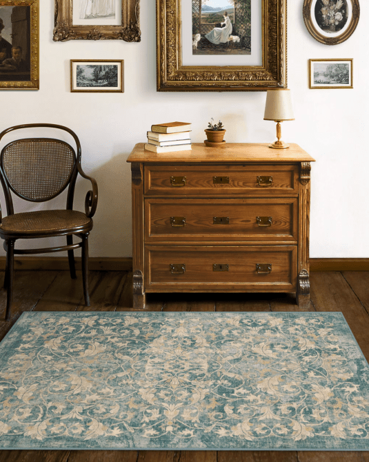 A room with antique furniture, vintage picture frames, and a distressed blue and white printed rug