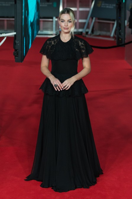 Margot Robbie wearing a black dress with ruffle details.