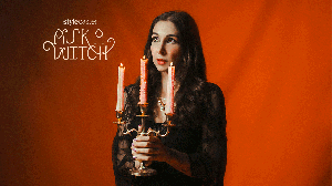 Woman holding a candlestick with flickering flames in front of an orange backdrop