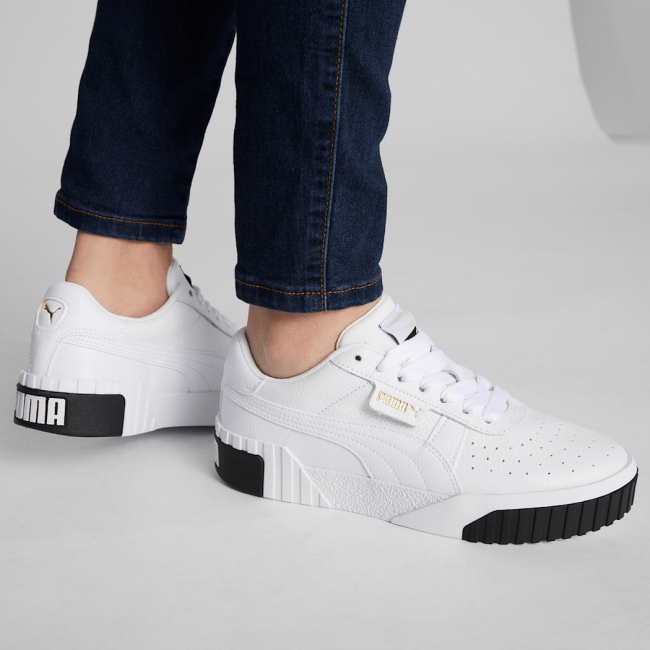 A close up of a model wearing the Puma Cali Sneakers in white and black