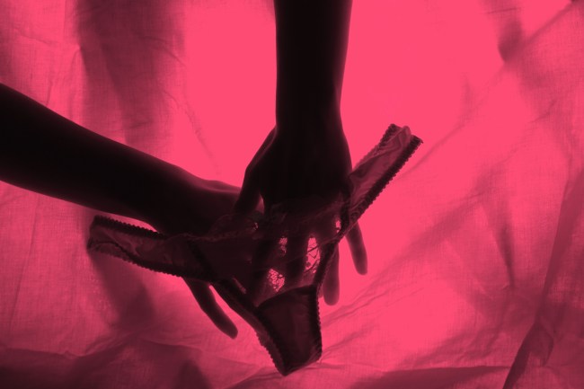 Woman hands and panties in pink light in representation of a cervix orgasm