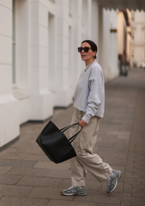 A woman in a gray sweatshirt, linen pants and sneakers in Hamburg, Germany.