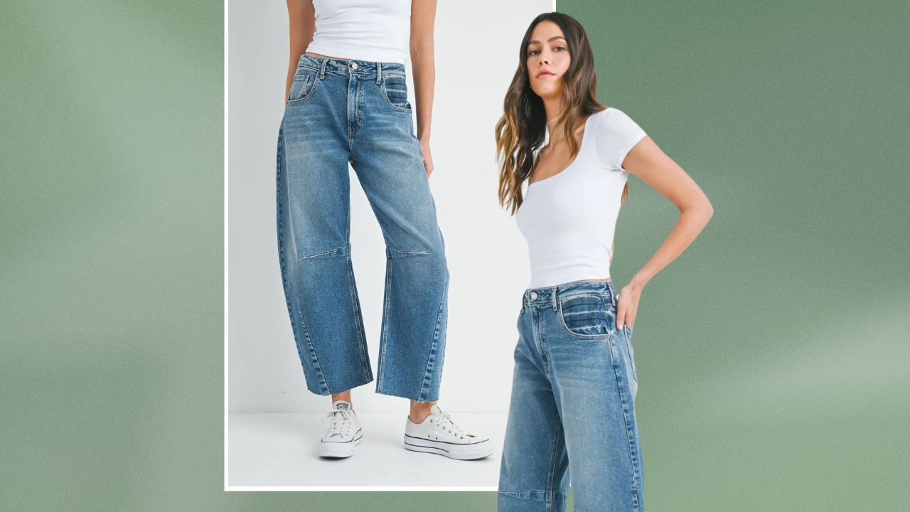 A woman wearing a white t-shirt and blue denim barrel jeans on a green background.