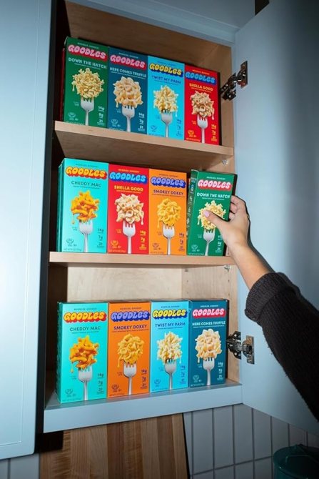 A hand reaching for a box of Mac & Cheese