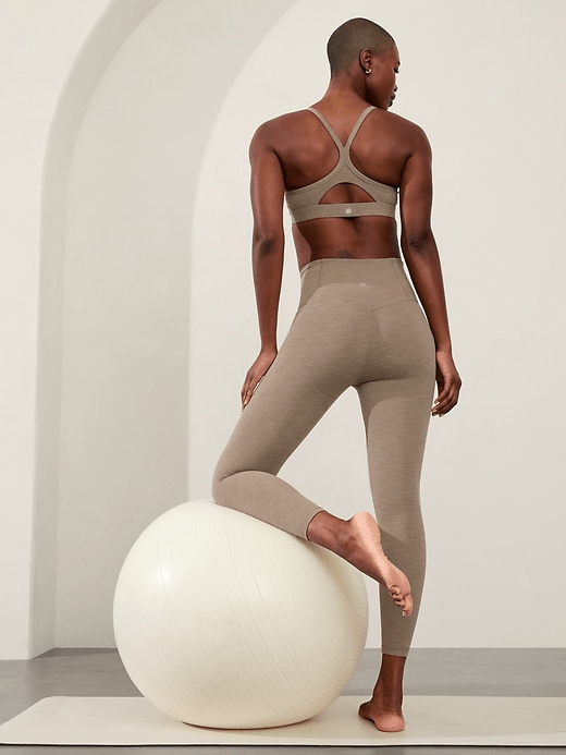 A model wearing the Athleta Elation Ultra High Rise 7/8 Legging in light brown colorway