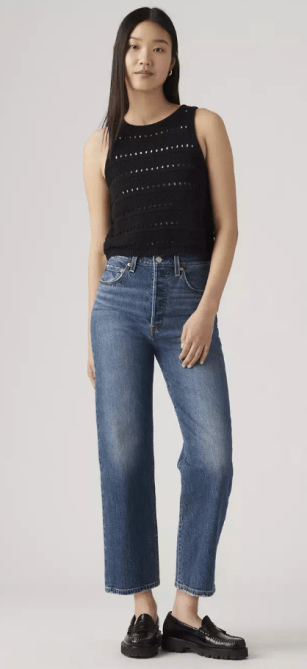 A woman in a black tank top and blue cropped jeans