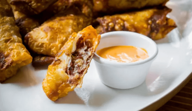 A plate of eggrolls filled with corned beef and sauerkraut