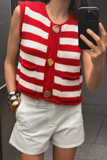 A model wearing the Zara Striped Knit Vest Top in white and red stripe with big gold buttons down the middle front