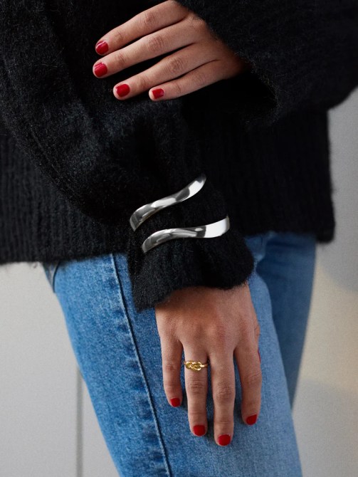 A woman in a black sweater with two silver bangle bracelets