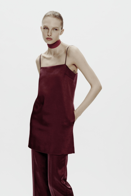 A model wearing the Zara Heavy Satin Dress in burgundy with matching pants and a choker necklace