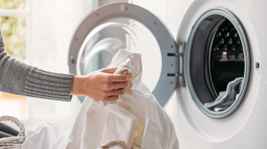 A close up of a woman putting dirty laundry in a washing machine