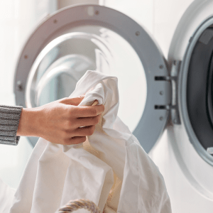 A close up of a woman putting dirty laundry in a washing machine