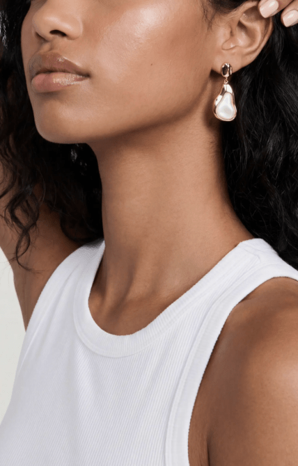 A woman wearing oversized pearl drop earrings